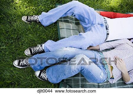 Picture - Young couple laying outdoors. Fotosearch
