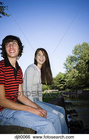 Young couple sitting outdoors View Large Photo Image Stock Photograph - Young couple sitting outdoors. Fotosearch