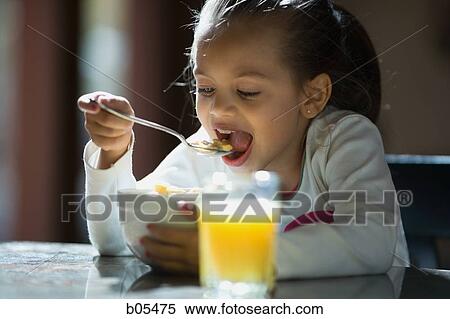 Young girl eating cereal and glass of orange juice View Large Photo Image Stock Photography - Young girl eating cereal and glass of orange juice. Fotosearch