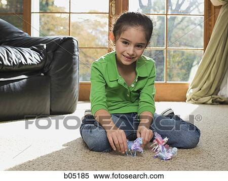 Stock Photography - Young girl playing with toys on carpet. Fotosearch