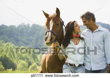 Stock Image - A Man and a woman standing with a horse. Fotosearch