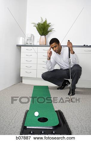 African-American businessman playing with golf putting machine View Large Photo Image Stock Photo - African-American businessman playing with golf putting machine. Fotosearch