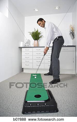 African-American businessman playing with golf putting machine View Large Photo Image Stock Photo - African-American businessman playing with golf putting machine. Fotosearch