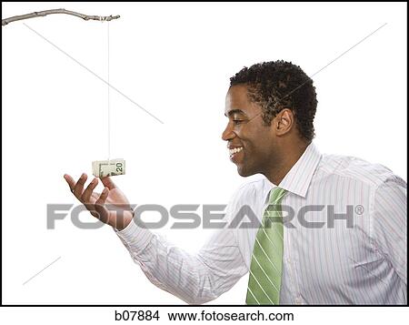 African-American businessman reaching for money roll lure View Large Photo Image Picture - African-American businessman reaching for money roll lure. Fotosearch