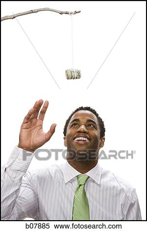 African-American businessman reaching for money roll lure View Large Photo Image Stock Photography - African-American businessman reaching for money roll lure. Fotosearch