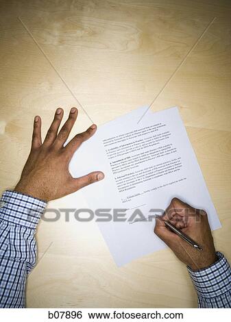 Stock Photograph - African-American man signing paperwork. Fotosearch