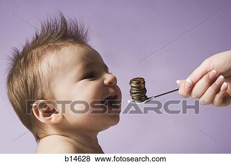 Stock Photo - Baby with spoon and stack of coins. Fotosearch