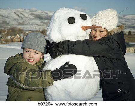 Brother and sister hugging snowman View Large Photo Image Picture - Brother and sister hugging snowman. Fotosearch