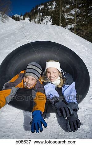 Stock Photo - Brother and sister sliding on inner tube. Fotosearch