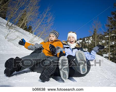 Stock Photo - Brother and sister sliding on inner tube. Fotosearch
