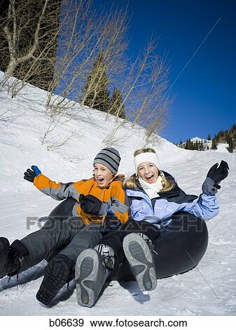 Stock Photo - Brother and sister sliding on inner tube. Fotosearch