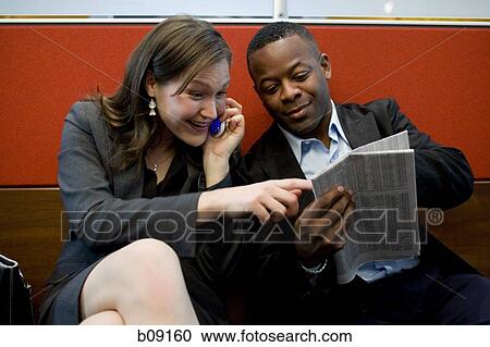 Stock Image - Businessman and a businesswoman reading a newspaper. Fotosearch