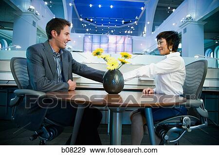 Businessman and a businesswoman shaking hands at the table View Large Photo Image Stock Photo - Businessman and a businesswoman shaking hands at the table. Fotosearch