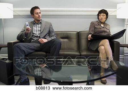 Businessman sitting with a businesswoman on a couch View Large Photo Image Stock Image - Businessman sitting with a businesswoman on a couch. Fotosearch