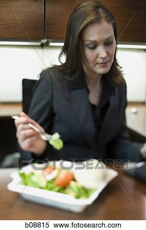 Businesswoman eating a salad at her desk View Large Photo Image Stock Photography - Businesswoman eating a salad at her desk. Fotosearch