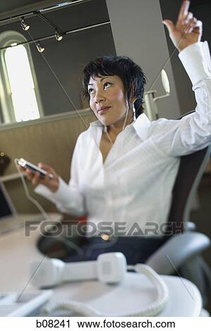Businesswoman listening to an MP3 player View Large Photo Image Stock Image - Businesswoman listening to an MP3 player. Fotosearch