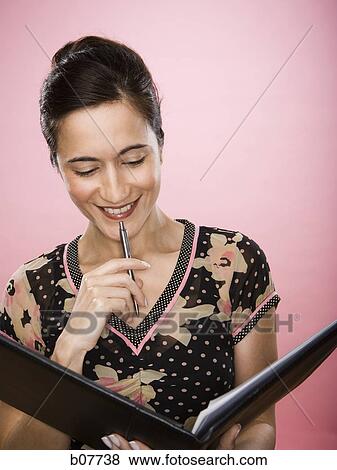 Businesswoman reviewing documents in a binder View Large Photo Image Stock Photo - Businesswoman reviewing documents in a binder. Fotosearch