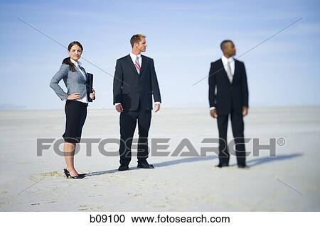 Stock Image - Businesswoman standing with two businessmen. Fotosearch