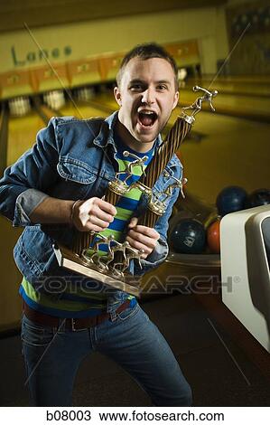 Stock Image - Champion bowler showing off trophy. Fotosearch