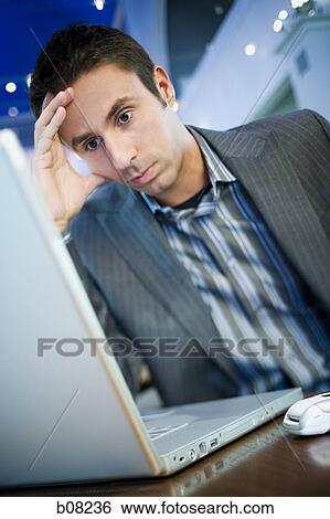 Close-up of a businessman sitting with his head in his hands in front of a laptop View Large Photo Image Stock Photograph - Close-up of a businessman sitting with his head in his hands in front of a laptop. Fotosearch