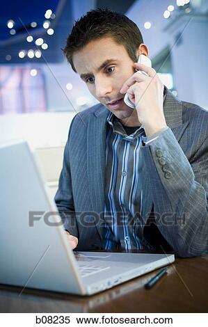 Close-up of a businessman talking on a cell phone in front of a laptop View Large Photo Image Stock Photography - Close-up of a businessman talking on a cell phone in front of a laptop. Fotosearch