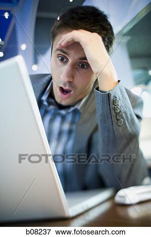 Close-up of a businessman with his head in his hands in front of a laptop View Large Photo Image Stock Photo - Close-up of a businessman with his head in his hands in front of a laptop. Fotosearch