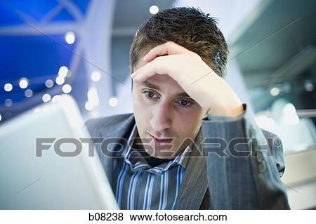 Close-up of a businessman with his head in his hands in front of a laptop View Large Photo Image Stock Photo - Close-up of a businessman with his head in his hands in front of a laptop. Fotosearch