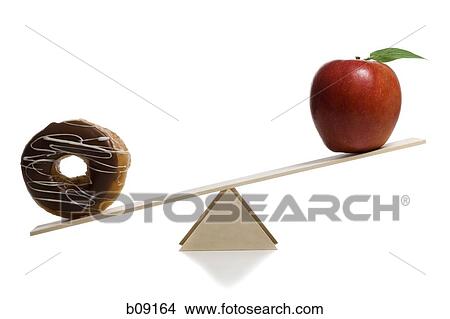 Picture - Close-up of a donut and an apple on a seesaw. Fotosearch