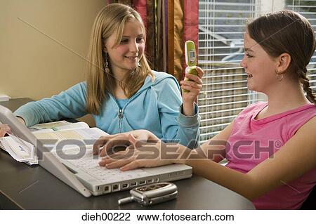 Stock Image - Close-up of a girl using a laptop with another girl operating a mobile phone. Fotosearch