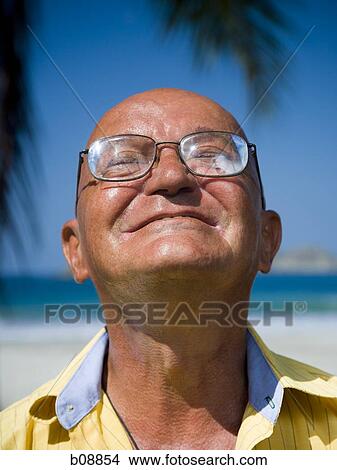 Close-up of a man smiling with his eyes closed on the beach View Large Photo Image Picture - Close-up of a man smiling with his eyes closed on the beach. Fotosearch