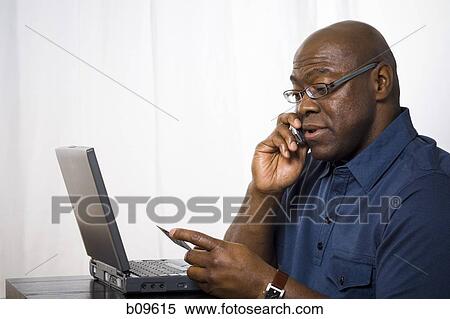 Close-up of a man talking on a mobile phone and holding a credit card View Large Photo Image Stock Photography - Close-up of a man talking on a mobile phone and holding a credit card. Fotosearch