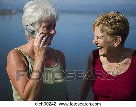 Close-up of a mature woman talking on a mobile phone with a senior woman View Large Photo Image Stock Image - Close-up of a mature woman talking on a mobile phone with a senior woman. Fotosearch