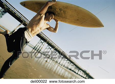 Close-up of a mid adult man holding a surfboard View Large Photo Image Stock Image - Close-up of a mid adult man holding a surfboard. Fotosearch