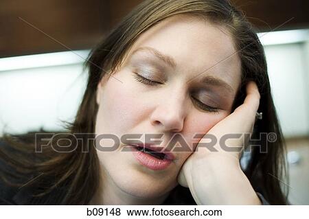 Stock Photo - Close-up of a mid adult woman sleeping with her head in her hands. Fotosearch