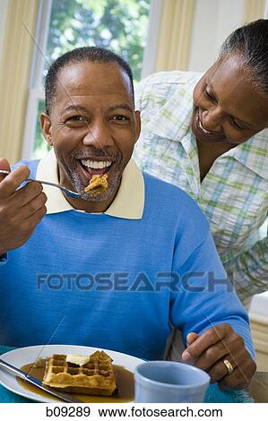 Close-up of a senior man having breakfast with a senior woman behind him View Large Photo Image Stock Photo - Close-up of a senior man having breakfast with a senior woman behind him. Fotosearch