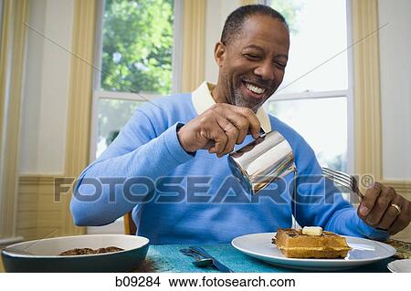 Close-up of a senior man pouring syrup on his waffle View Large Photo Image Picture - Close-up of a senior man pouring syrup on his waffle. Fotosearch