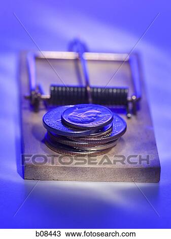 Stock Image - Close-up of a stack of coins on a mousetrap. Fotosearch