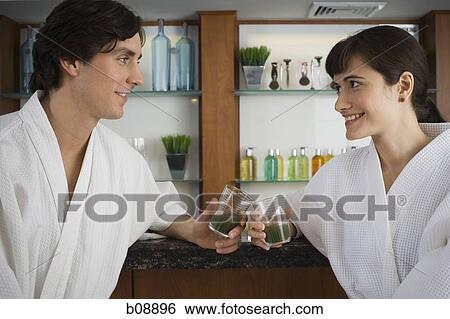 Close-up of a young couple holding glasses of wheatgrass juice View Large Photo Image Stock Photograph - Close-up of a young couple holding glasses of wheatgrass juice. Fotosearch