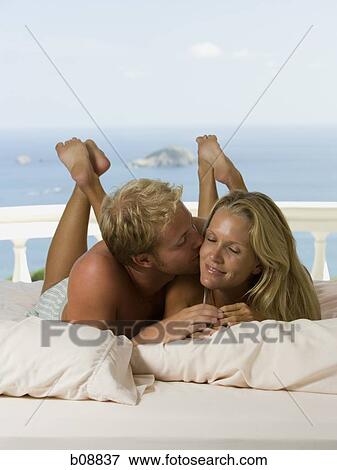 Close-up of a young man kissing a woman View Large Photo Image Stock Photo - Close-up of a young man kissing a woman. Fotosearch
