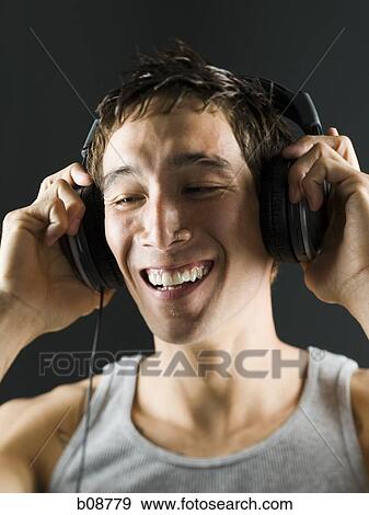 Close-up of a young man with headphones on View Large Photo Image Stock Photo - Close-up of a young man with headphones on. Fotosearch