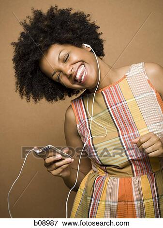 Close-up of a young woman listening an MP3 player View Large Photo Image Stock Photo - Close-up of a young woman listening an MP3 player. Fotosearch