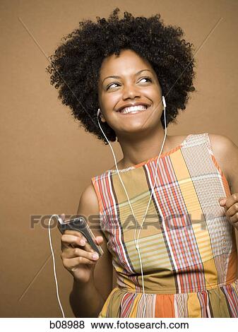 Close-up of a young woman listening an MP3 player View Large Photo Image Stock Photo - Close-up of a young woman listening an MP3 player. Fotosearch