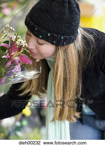 Stock Image - Close-up of a young woman smelling flowers. Fotosearch