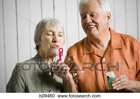 Close-up of an elderly couple blowing bubbles with a bubble wand View Large Photo Image Stock Image - Close-up of an elderly couple blowing bubbles with a bubble wand. Fotosearch