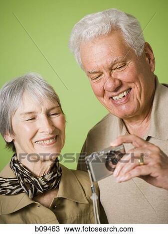 Close-up of an elderly couple looking at a digital camera View Large Photo Image Stock Image - Close-up of an elderly couple looking at a digital camera. Fotosearch