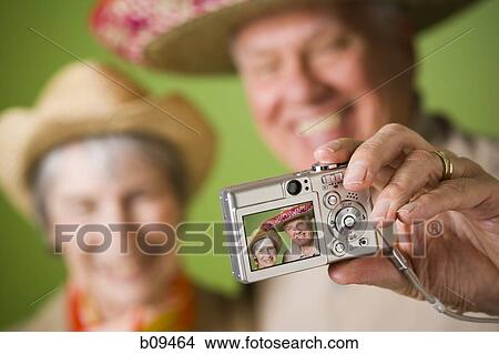 Close-up of an elderly couple taking a photograph of themselves View Large Photo Image Picture - Close-up of an elderly couple taking a photograph of themselves. Fotosearch