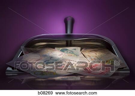 Stock Photo - Close-up of British pounds in a dustpan. Fotosearch