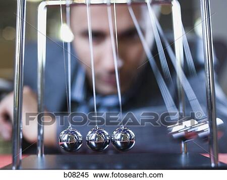 Stock Photography - Close-up of businessman watching a Newton's cradle. Fotosearch