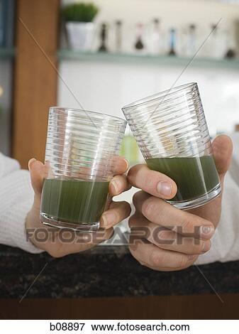 Close-up of two person's hands toasting with glasses of wheatgrass juice View Large Photo Image Stock Photo - Close-up of two person's hands toasting with glasses of wheatgrass juice. Fotosearch