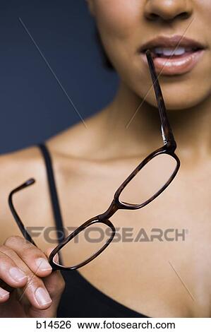 Closeup of woman holding eyeglasses and biting arm View Large Photo Image Stock Photograph - Closeup of woman holding eyeglasses and biting arm. Fotosearch